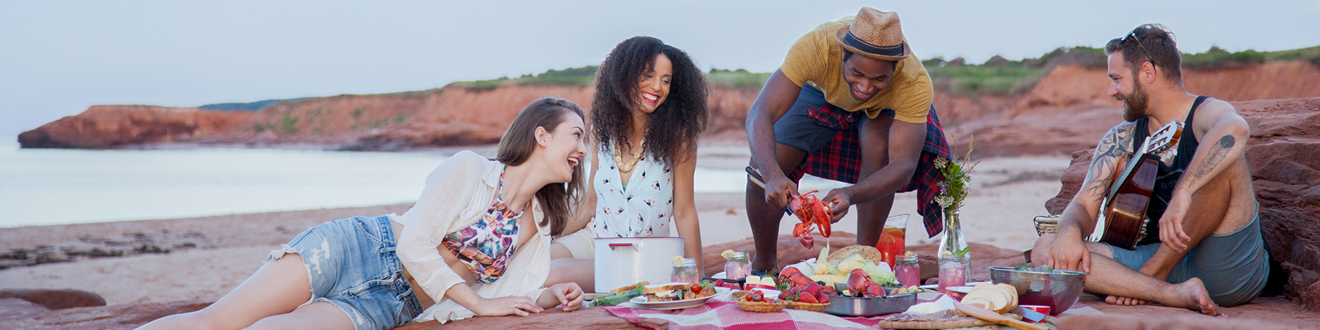 Four people enjoy a meal on the red rocks by the ocean