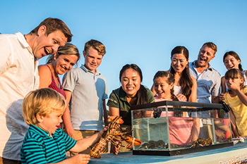 A child explores lobster with their family. 