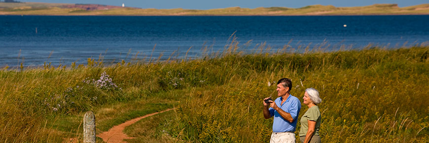 Two seniors birdwatching with binoculars in PEI National Park.