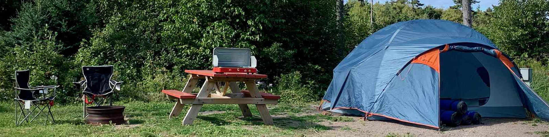 Tent, picnic table and chairs in a campsite. 