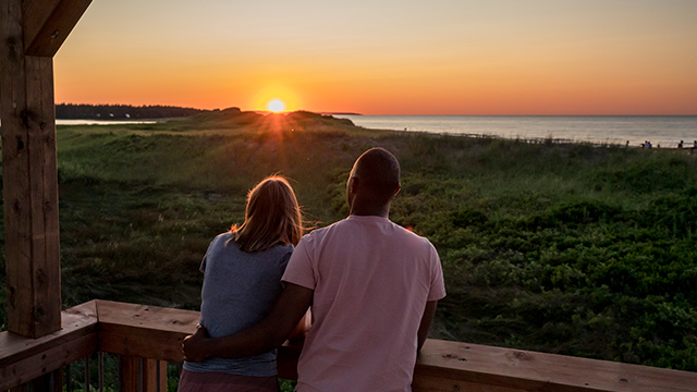 Two people watch the sun rise in Cavendish PEI