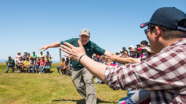 Un employé de Parcs Canada interagit avec les participants à un cours de « Camping 101 » dans le cadre de l’activité Initiation au camping au terrain de camping de Cavendish. Parc national de l’Île-du-Prince-Édouard.