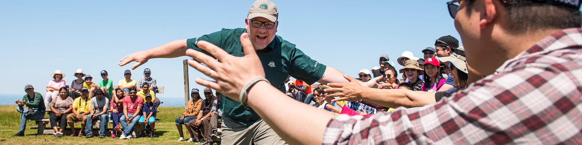 Un employé de Parcs Canada interagit avec les participants à un cours de « Camping 101 » dans le cadre de l’activité Initiation au camping au terrain de camping de Cavendish. Parc national de l’Île-du-Prince-Édouard.