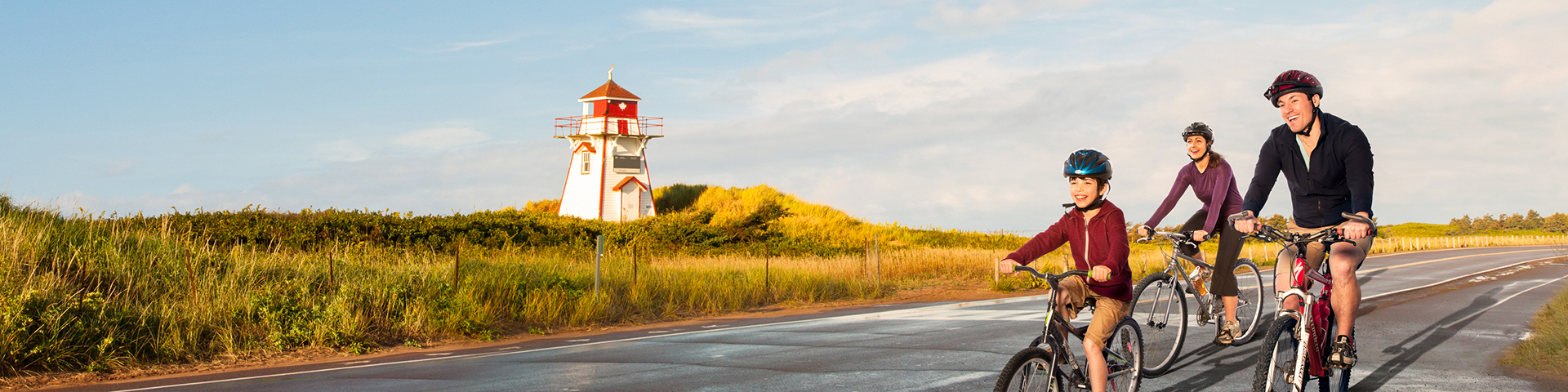 Une famille passe à vélo devant un phare