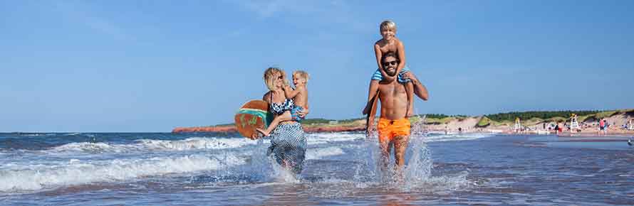 Parents and their kids splash in the water in PEI National Park.