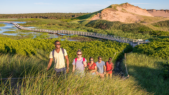 A group of friends hike along the Havre-Saint-Pierre trail at Greenwich with a view of the dunes in the background. Prince Edward Island National Park.