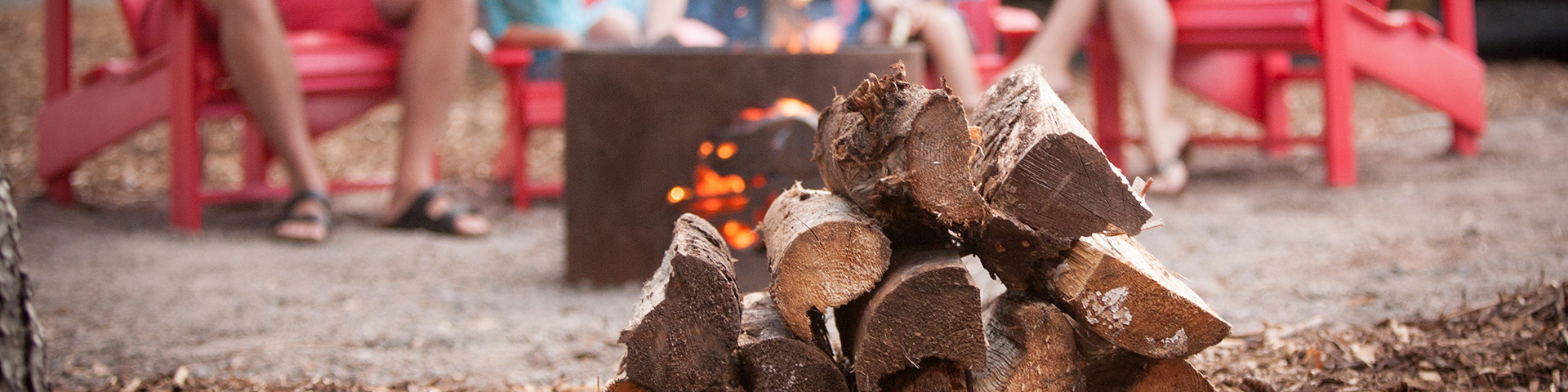 A stack of firewood sits in front of a Parks Canada fire ring.