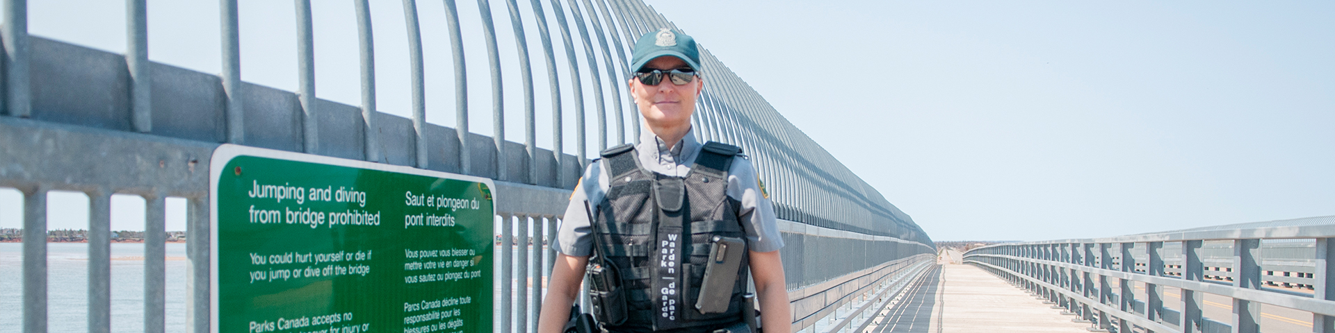 Park warden stands next to a safety sign on Covehead bridge