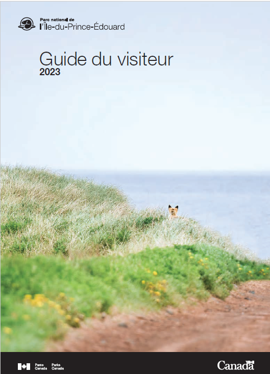 La couverture du guide du visiteur du parc national de l'Î.-P.-É. pour 2021, qui montre un jeune homme et une jeune femme regardant le coucher du soleil à Cavendish. 