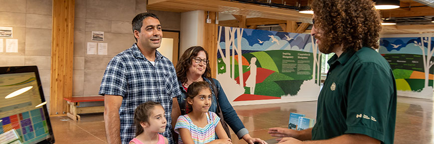 A Parks Canada visitor services attendant speaks with a family at Green Gables Heritage Place. 
