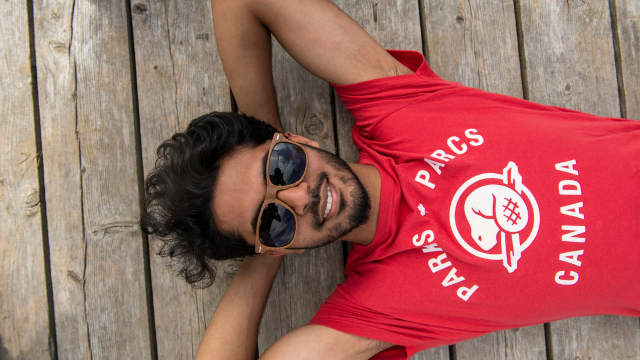A young adult stretches out on a wooded floor on a sunny day.