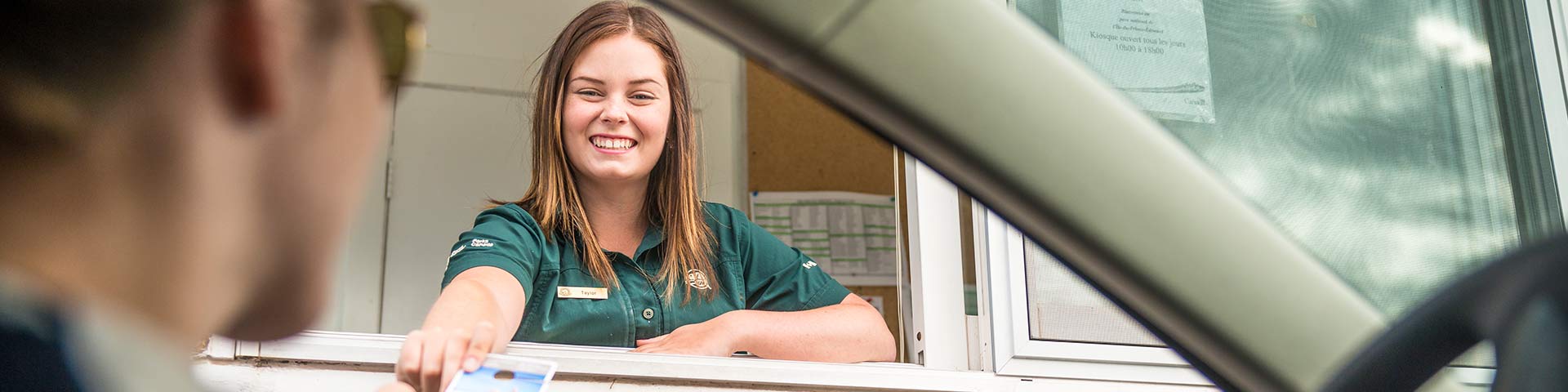 Parks Canada staff hands out visitor information at the entrance kiosk at Cavendish Campground. Prince Edward Island National Park.