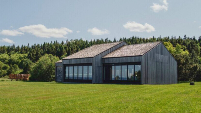 Bâtiment de bois dans un champ gazonné. 