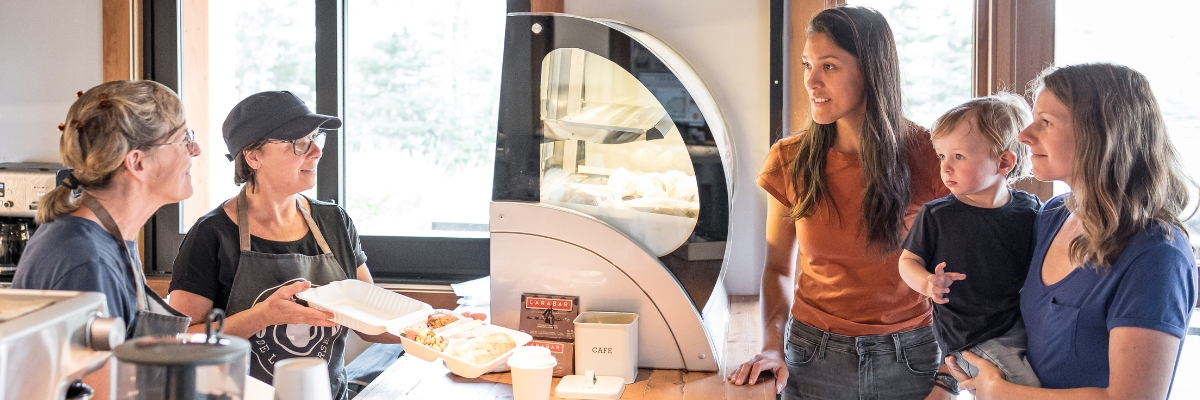 Deux visiteuses et un enfant reçoivent leur gouter d'employées du petit Café de la Traverse.