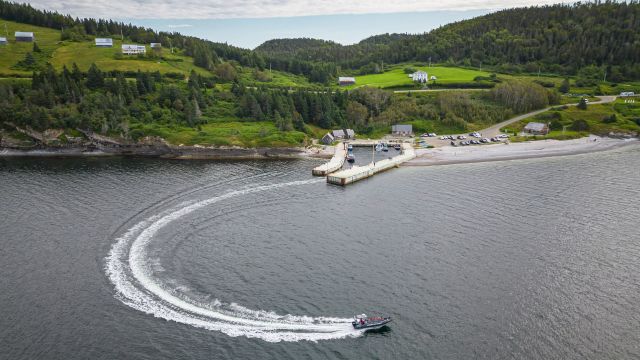 Aerial view of a boat leaving a dock, creating a C-shaped wake. 