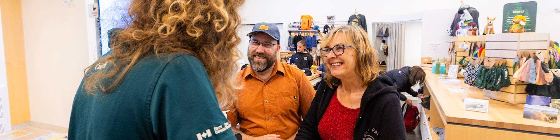 Two visitors are chatting with a member of staff near the Parks Canada shop. 
