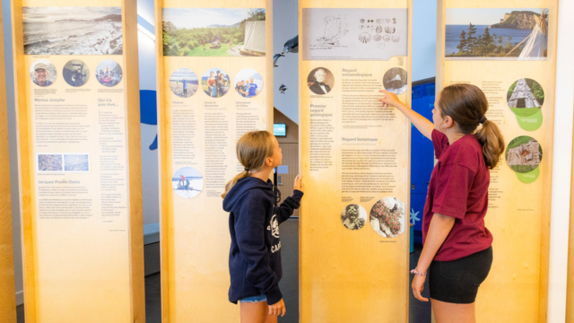 Two young visitors are reading texts on an interpretation panel.