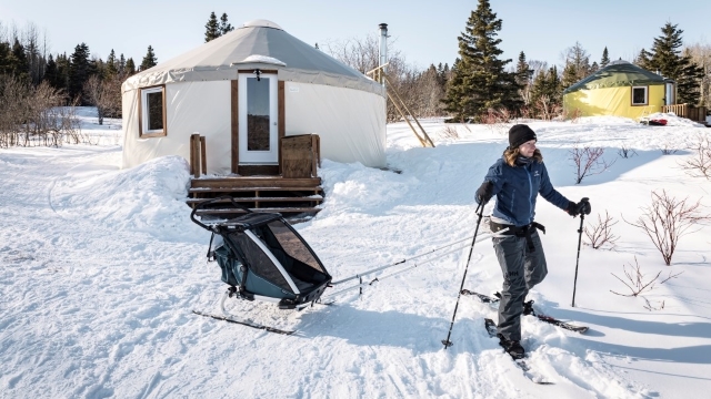 A skier towing a baby glider quits the site of a yurt. 