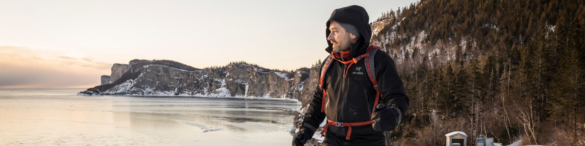 Un skieur regarde le paysage de mer et de falaises. 