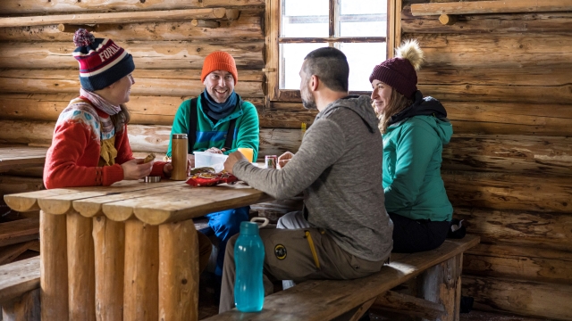 Groupe de personnes bavardant à la table d'un chalet de bois rond