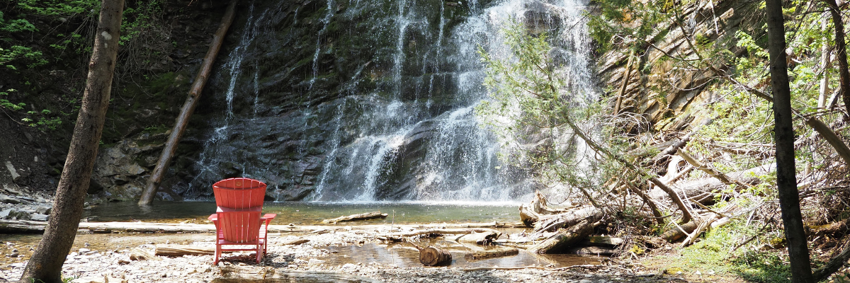 Red chair in front of a waterfall in summer.