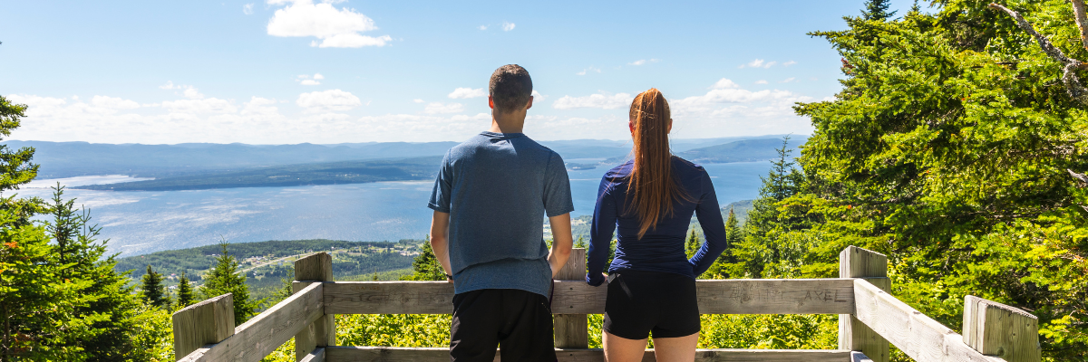 Two people are looking out over the view of Gaspé Bay from a lookout point.