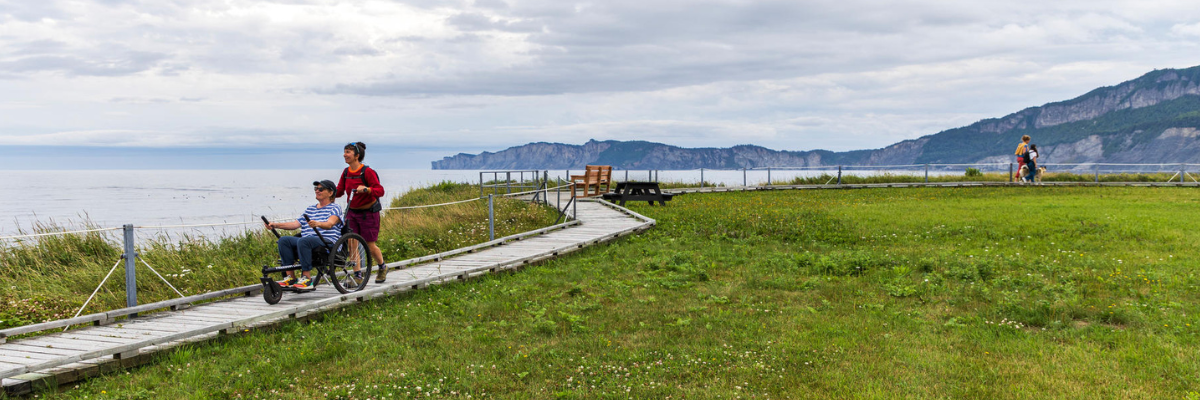 Two women, one in a wheelchair, go along a boardwalk