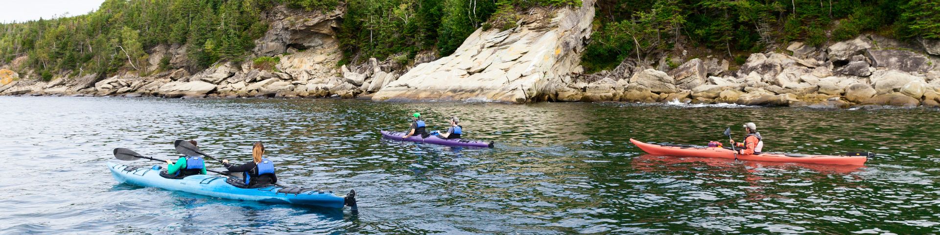 A man in a wheelchair looks out over the sea on a universal carpet set up on a beach.