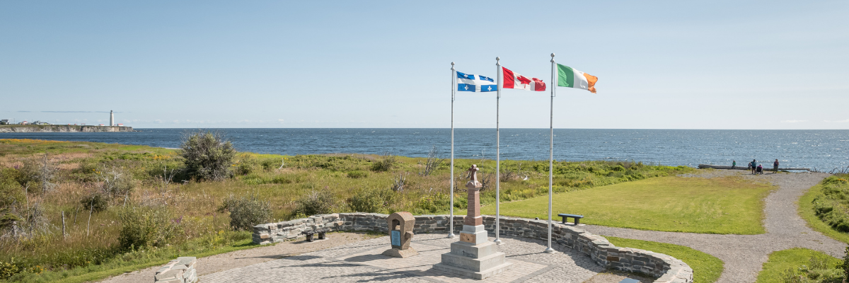 Near the beach, a commemorative area features two monuments and Canadian, Quebec and Irish flags. 