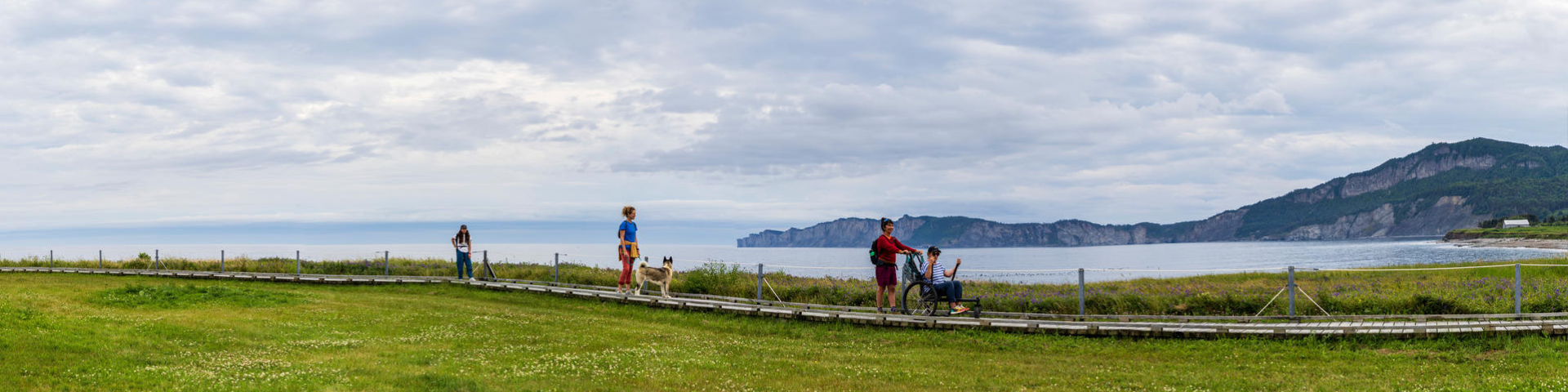 Des visiteurs profitent du sentier Prélude-à-Forillon et admirent la vue sur la mer et les falaises. 