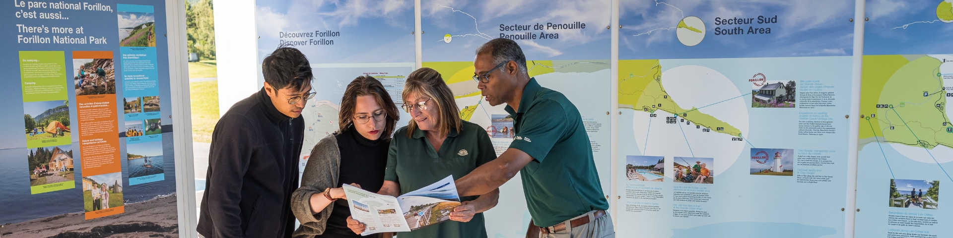Deux employées aident deux visiteurs à s'orienter au parc è l'aide d'une brochure.