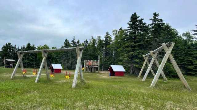 A playground with swings and little cabins for kids. 