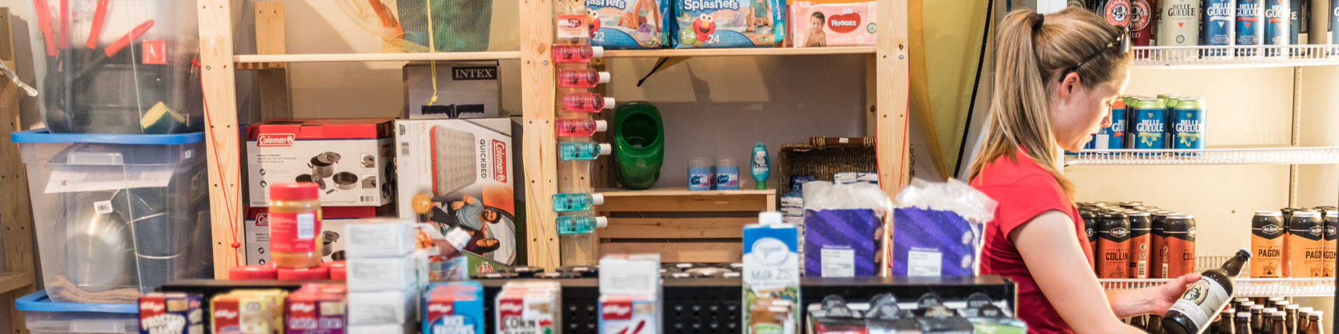 Deux tasses de fer avec le logo du castor de Parcs Canada sont posées sur une galerie devant bâtiment historique.