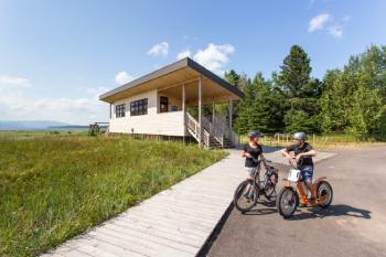 Deux cyclistes prennent un pause près d'un bâtiment de service de bois.