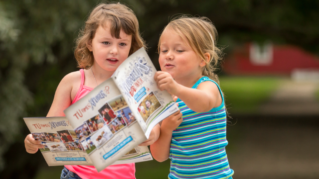 Two girls hold an Xplorator booklet.