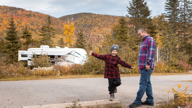 Un enfant et son père s'amusent dehors près d'un site de camping.