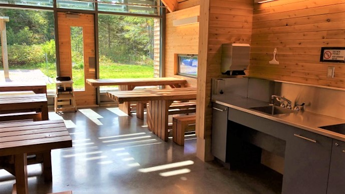 L'intérieur d'un des bâtiments de service du camping Petit-Gaspé, avec tables adaptées pour personnes à mobilité réduite et un lavabo