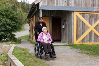 A woman in a wheelchair and a friend in front of a service building.