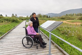 A woman in a wheelchair and a friend are reading an interpretation panel