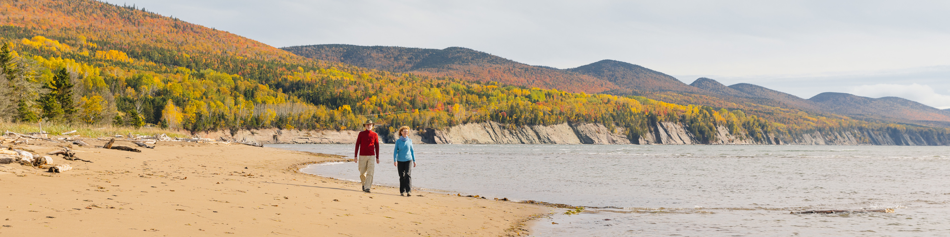 Deux personnes marchent sur une plage de galet.