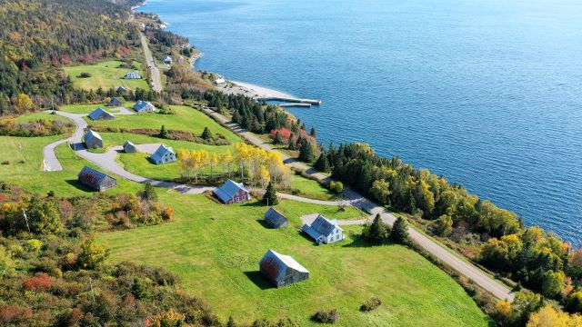 Vue aérienne de maisons patrimoniales à flanc de côteau près de la baie. 