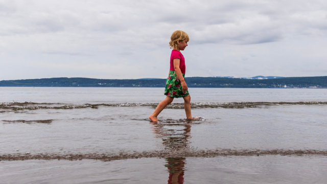 A little girl is walking on a sandbank near Penouille beach. 