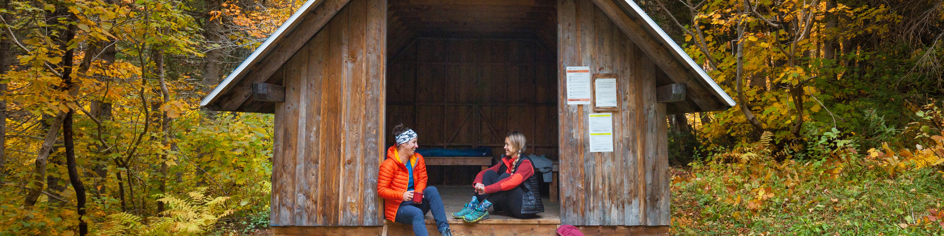 Two campers chat at the doorstep of a shelter. 