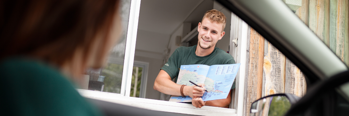Un employé au kiosque d'entrée du parc Forillon donne des informations à un automobiliste.