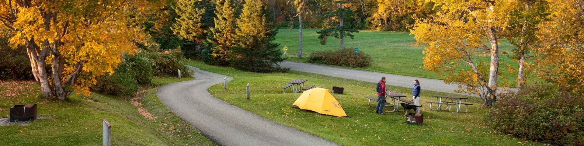 Deux campeurs discutent près de leur tente au camping Cap-Bon-Ami en automne.