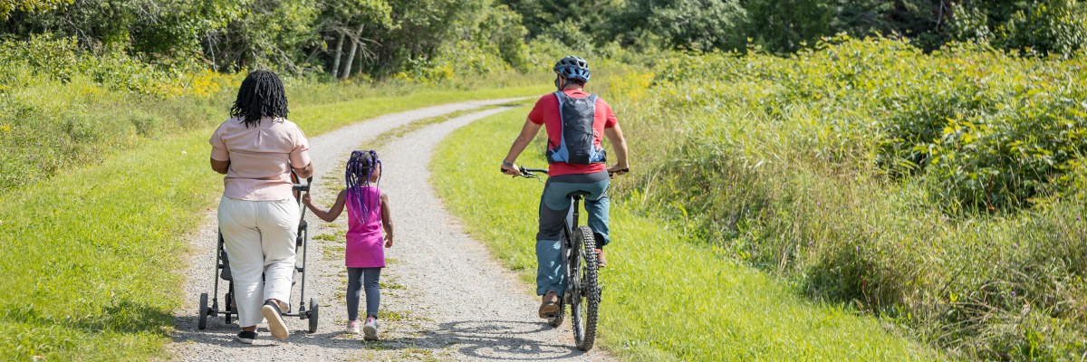 A mountain biker passes next to a mother and her child who walk on a trail. 