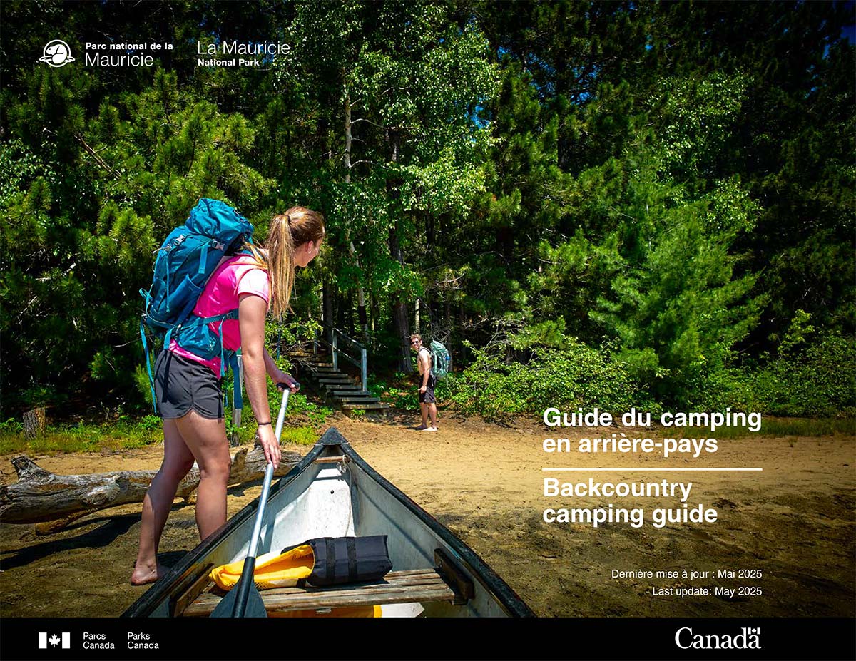 2025 backcountry camping guide cover - a young canoer hauls her canoe on a beach.