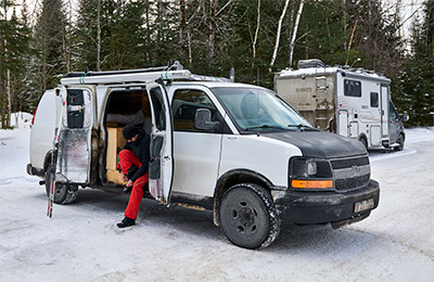 A vanlife camper is parked in the snow.