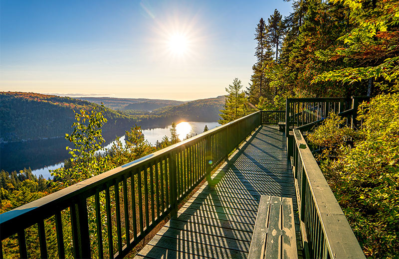 A wooden lookout with a view of a lake and hills.