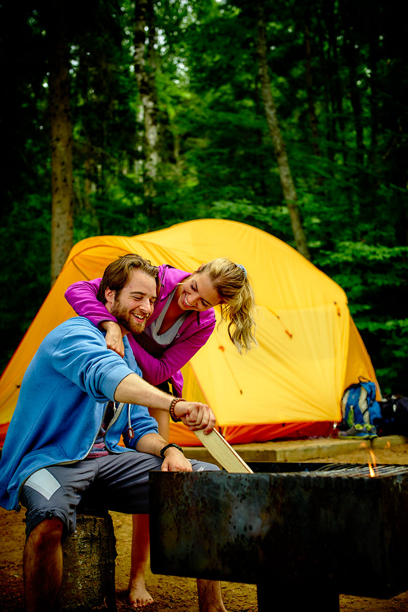 Un couple devant une tente jaune dans le bois
